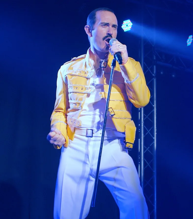 Eddie Devlin as Freddie Mercury in the yellow jacket, singing live